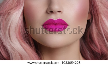 Close-up of woman\'s lips with fashion bright pink make-up. Beautiful female mouth, full lips with perfect makeup. Part of female face. Choice lipstick. Pink wavy hair of a Barbie doll