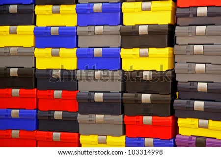 Large pile of colorful plastic closed tool boxes