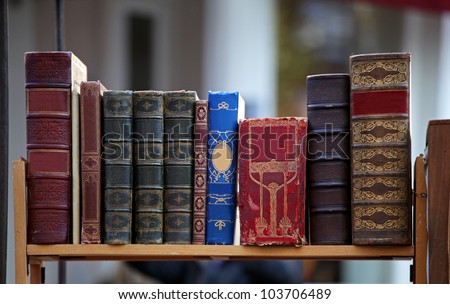 Old grunge books in leather binding on wooden shelf