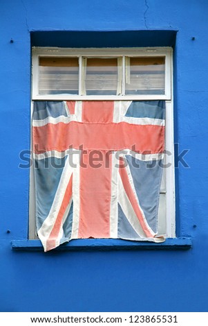 Washed out British flag covering window on house with blue facade