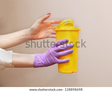 Medical waste container in female hands with surgical glove