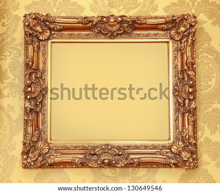 Gold Baroque frame with carved edges on beige wall