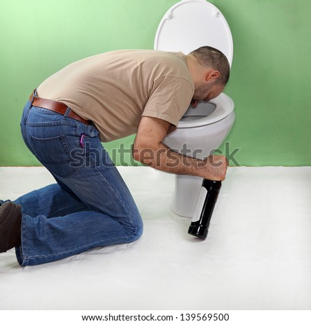 Drunk man with wine bottle vomiting in toilet