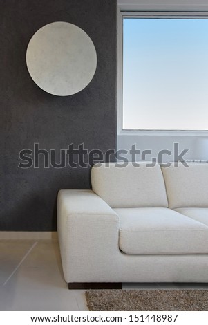 White sofa inside modern interior with circle mirror on wall