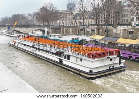 PARIS, FRANCE - January 6, 2010; Sightseeing tour boat in Paris, France - January 6, 2010; Famous tourist destination tour boat on Seine river in Paris with people onboard during winter festive season
