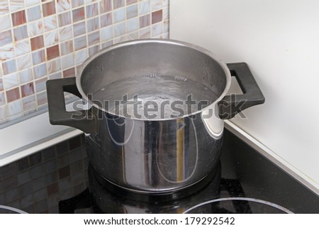 Water boiling in a pot on stove in modern kitchen