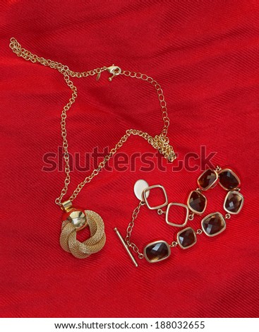 Shiny gold jewelry necklace and bracelet on red background