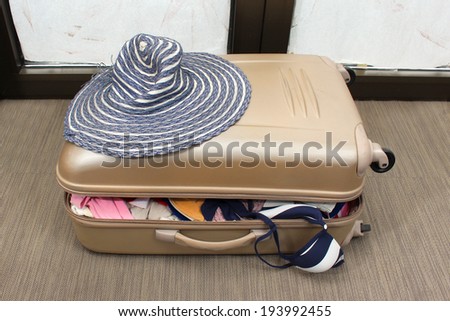 Overfilled suitcase with clothes packed for summer vacation