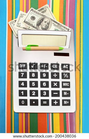 Calculator with dollar notes behind display and pen