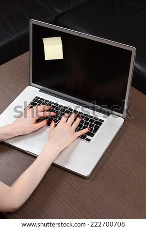 Female hands typing on modern laptop with post it attached on display