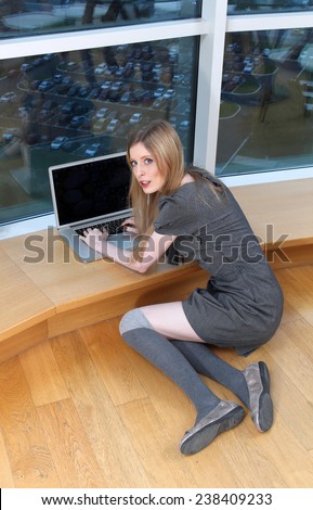 Young woman surprised by someone watching her while working on laptop