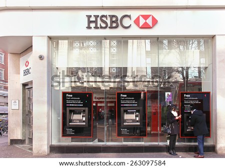 LONDON, UNITED KINGDOM - February 08: HSBC bank branch with glass wall on Oxford Street in London, UK - February 08, 2015; HSBC bank branch with people outside on street using ATM machines
