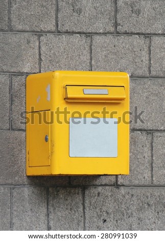 Small yellow post box on building wall outdoor