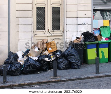 Large garbage pile inside black bags and green containers on street
