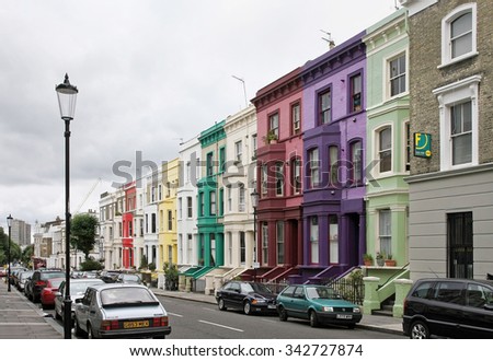 LONDON, UNITED KINGDOM - AUGUST 02: Colorful houses residential street with parked cars in Westminster London, UK - August 02, 2008; Cloudy London street with residential houses and parked cars.