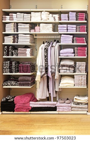 Big storage space with towels on shelf and bathrobes on hangers