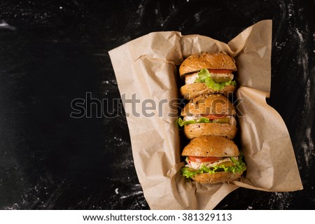 Three burgers on a dark background, in the craft, view from above