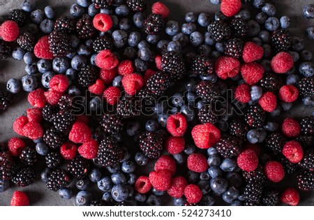 Raspberries, blackberries, blueberries a gray abstract background. Copyspace. Healthy food concept.  Colorful festive still life. Loosely laid berries in different positions