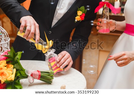 sand ceremony being performed at wedding. Hands of bride holding vase with colorful sand during wedding party