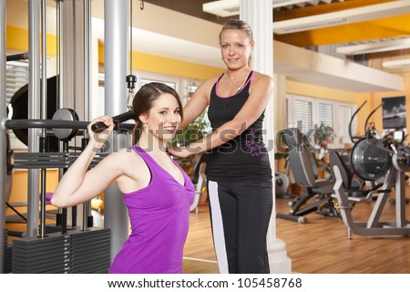 smiling young woman with her female coach training latissimus