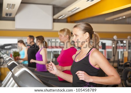 five young people training on treadmills at gym