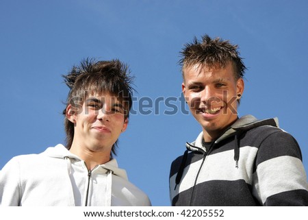 two smiling male teenage friends having fun, photographed in the summer sun with blue sky in the background