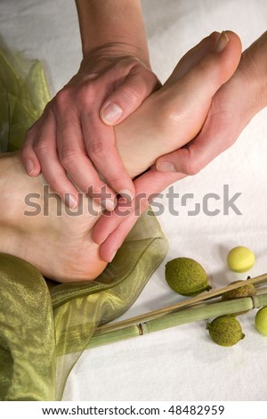 a wellness composition with a closeup of a foot of a mature natural woman having a foot massage