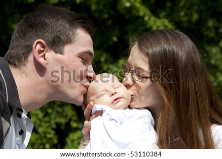 young parents kissing her sleeping 7 weeks old daughter