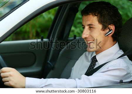 Smiling businessman driving a car with headset