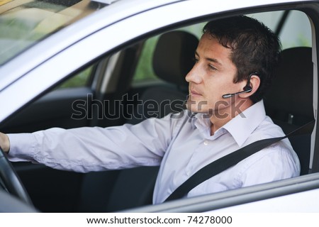 Businessman driving a car with blue-tooth hands-free