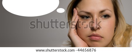 Blonde girl thinking.  A young woman in contemplation with a blank thought bubble above her head on gray background.