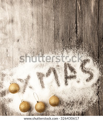 Christmas card with gold Christmas balls, snowballs, winter snow and star on wooden background.