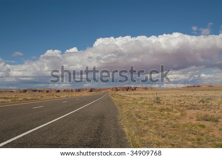 road without end with beautiful clouds and one small car at the end of de road