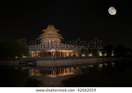 A corner of The Forbidden City, which is in Beijing China, reflected in the water, at night and with full moon.