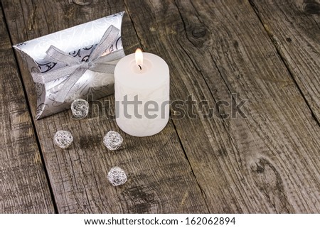 Christmas gift box with candle on wooden background