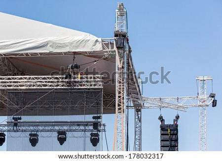 Professional lighting equipment high above an outdoor theatrical performance