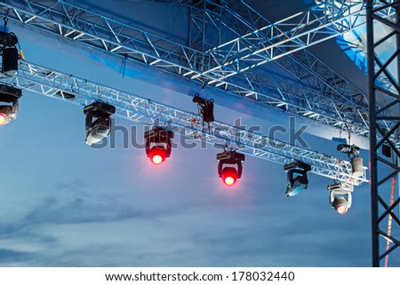 Professional lighting equipment high above an outdoor concert