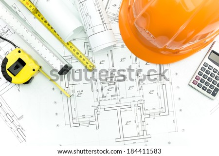 Construction plans with helmet and measurement tools on blueprints