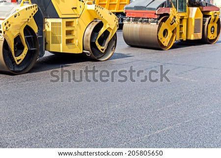 Steam road rollers compacting fresh asphalt during road repairing works