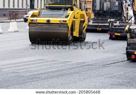 Steam roller machines compacting fresh asphalt during road repairing