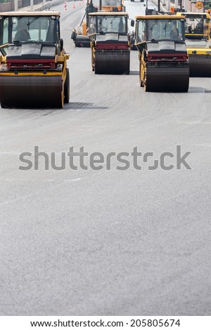 Steam rollers machines compacting fresh asphalt during road construction works