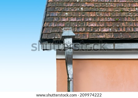 Old rain gutter with weathered tiled roof