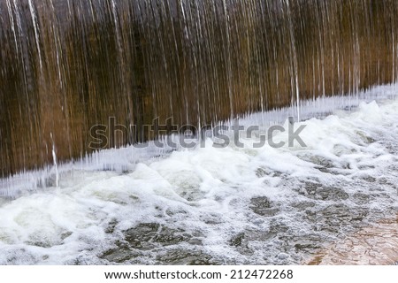 Polluted river waterfall with foam bubbles on the surface