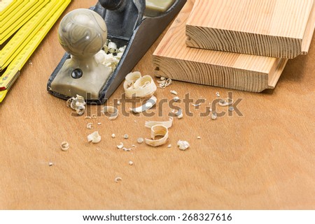 Carpenter\'s plane and folding rule with shaving on wooden background