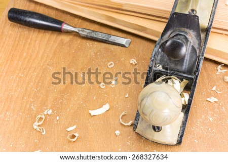 Carpenter\'s plane and chisel with shaving on a wooden background