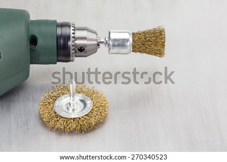 Electric drill with rotating metal brushes on scratched background