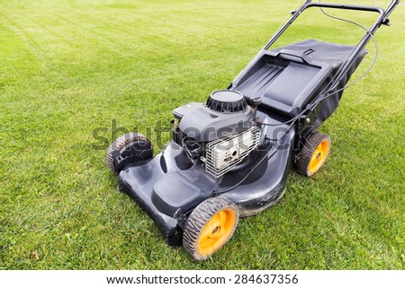 lawn mover cutting green grass on garden field