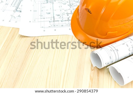 safety helmet with rolled blueprints and construction plans