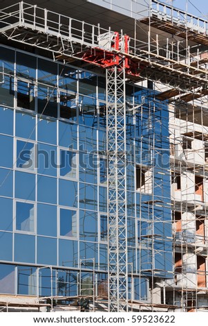 Modern buildings under construction. Metal scaffolding with wooden planks.