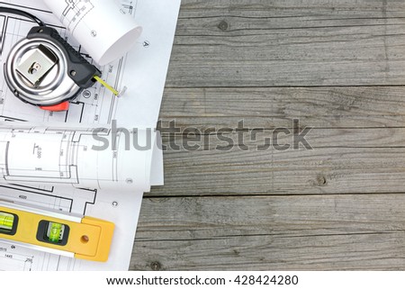 architectural blueprints with spirit level and tape measure on gray wooden boards